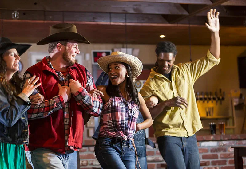 Group of friends line dancing at a western bar
